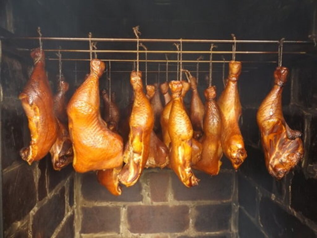 Goldbraun geräucherte Hähnchenschenkel im gemauerten Räucherofen